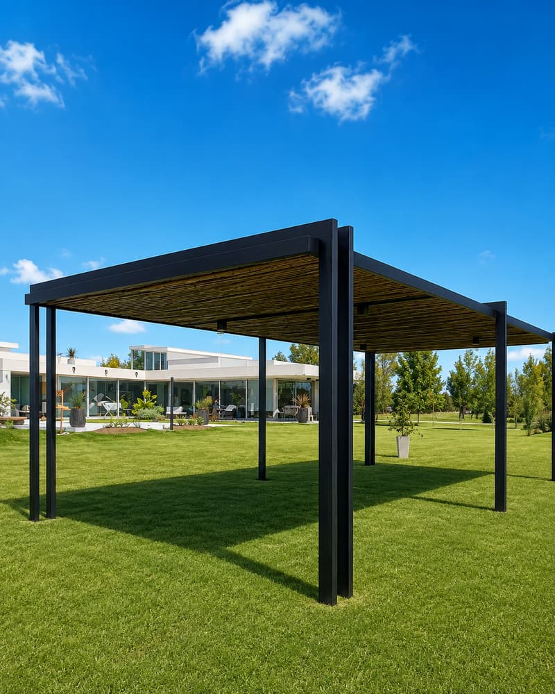 Pérgola de perfiles negros con techo de cañas, sobre el césped de un jardín
